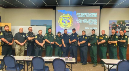 Group photo of law enforcement officers standing together in a classroom setting.